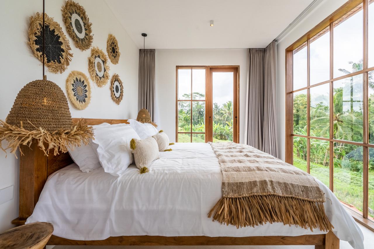 The bright bedroom in the villa is a paradise for lovers of space and light. Huge floor-to-ceiling windows allow you to enjoy the view of the endless rice fields that spread out outside the window.